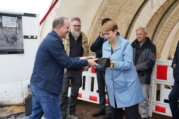 Staatssekretärin Andrea Lindlohr MdL mit dem Holzwerkzeug, das die frühkeltischen Erbauer der Grabkammer zurückgelassen haben