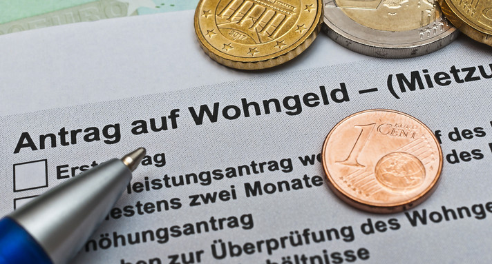 Antrag auf Wohngeld mit Kugelschreiber und Münzgeld