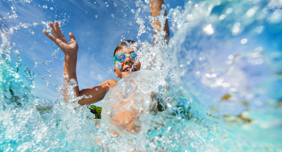 Kind mit Schwimmbrille spielt im Wasser