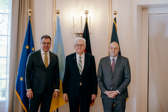 Besuch Kretschmann empfängt ukrainischen Botschafter Von links nach rechts: Der ukrainische Botschafter Oleksij Makeiev, Ministerpräsident Winfried Kretschmann und der ukrainische Generalkonsul Yurii Nykytiuk stehen vor Fahnen.