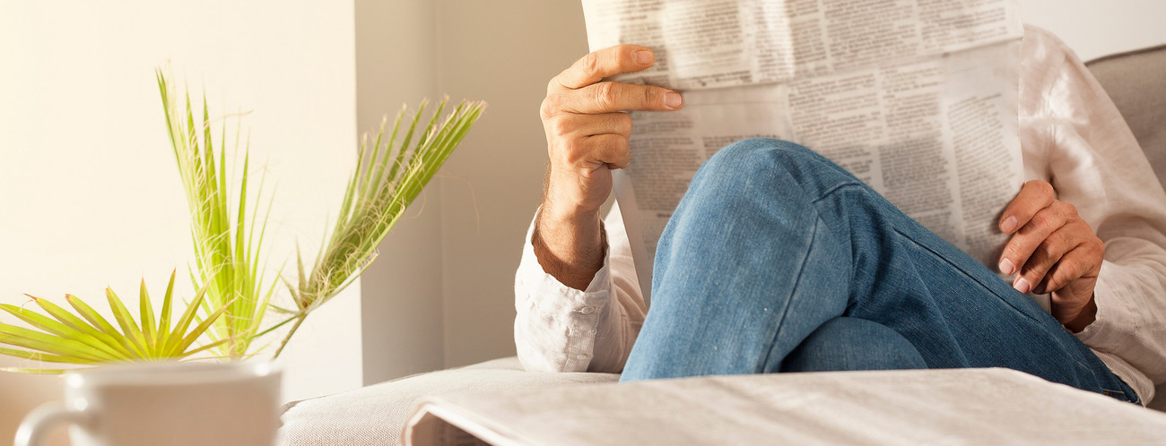 Mann liest Zeitung auf der Couch