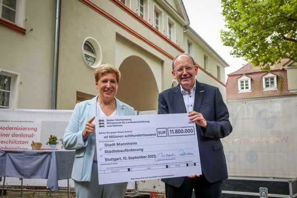 Denkmalreise Ministerin Razavi besichtigt Siedlung Reiherplatz in Mannheim-Käfertal Ministerin Nicole Razavi überreicht Mannheims Oberbürgermeister Christian Specht einen symbolischen Scheck der Städtebauförderung.