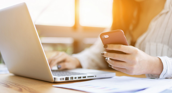 Geschäftsfrau arbeitet mit Laptop und Smartphone am Schreibtisch