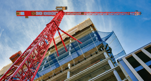 Baustelle, Blick von unten an einem roten Kran hoch