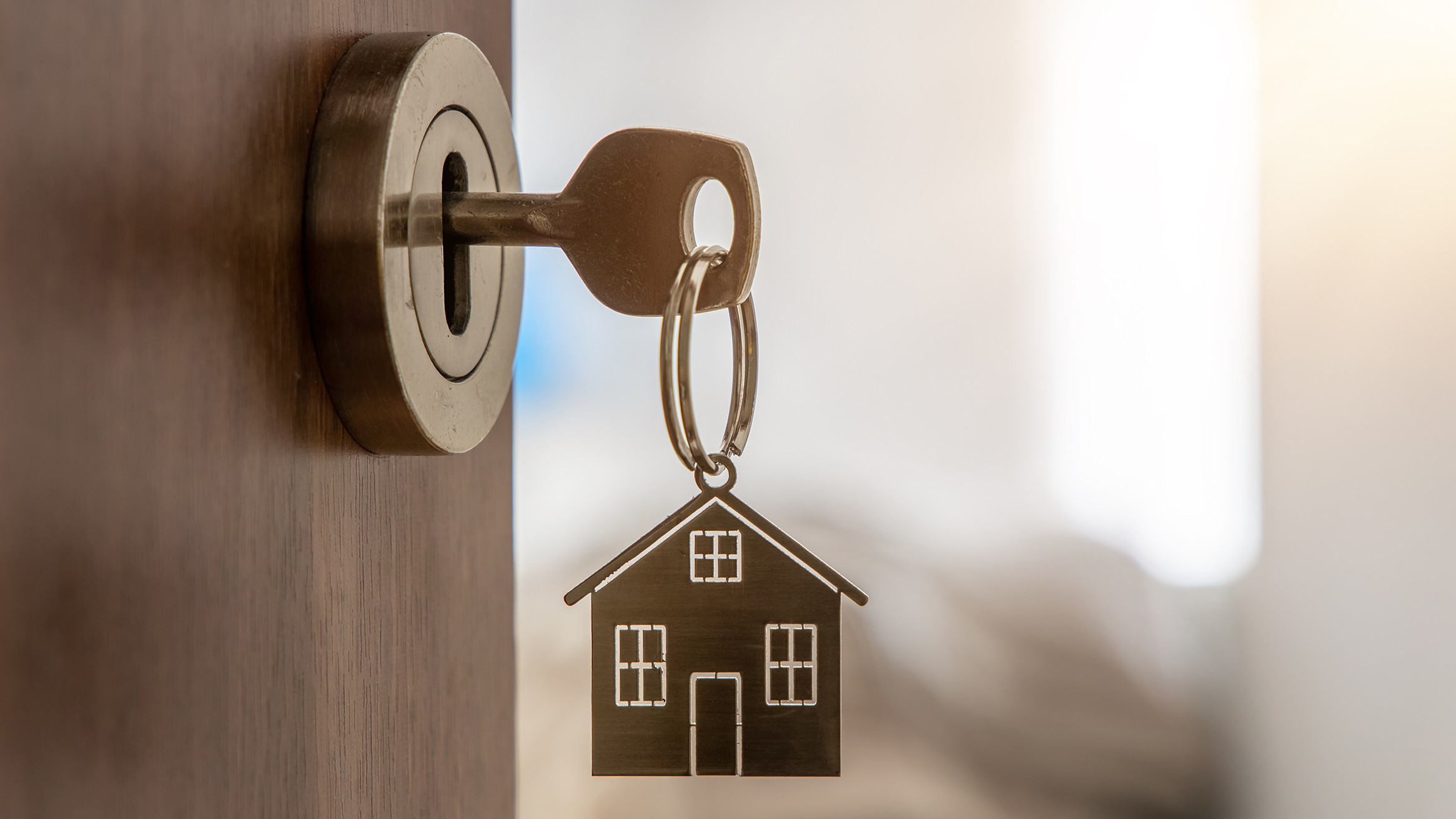 Schlüssel mit Hausminiatur-Anhänger an einer neuen Wohnungstür