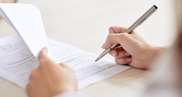 Person unterzeichnet einen Vertrag am Schreibtisch