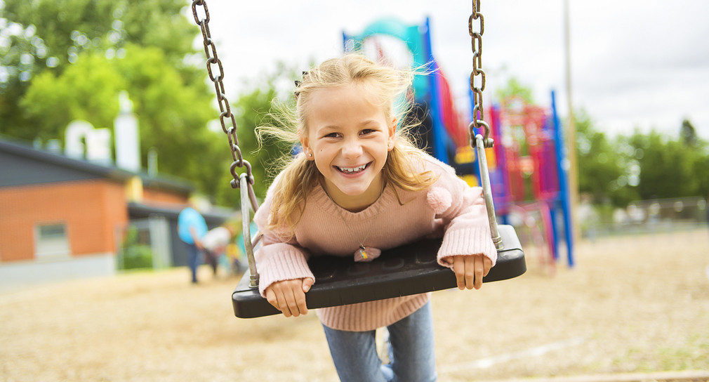 Ein Mädchen schaukelt auf einem Spielplatz