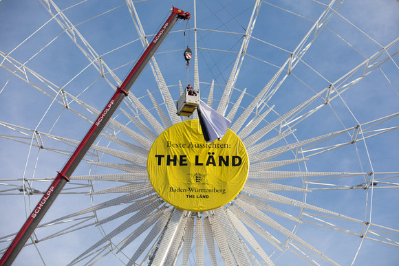 Imagekampagne Baden-Württemberg ist „THE LÄND“ Riesenrad auf dem Stuttgarter Schlossplatz mit der Aufschrift „Beste Aussichten: THE LÄND“ und dem Landeswappen