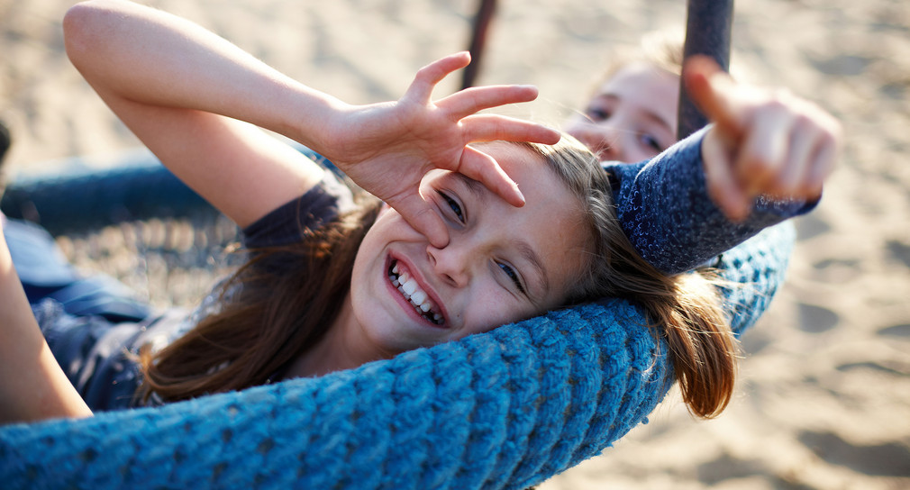 Zwei Schwestern in einer Nestschaukel auf dem Spielplatz