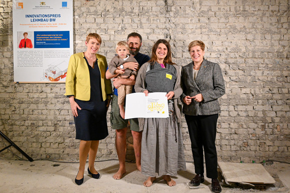 Staatssekretärin Andrea Lindlohr MdL (l.) und Ministerin Nicole Razavi MdL (r.) überreichen den Lehmbaupreis in der Kategorie Bauen im Bestand für das Projekt Leben im Lehmhaus