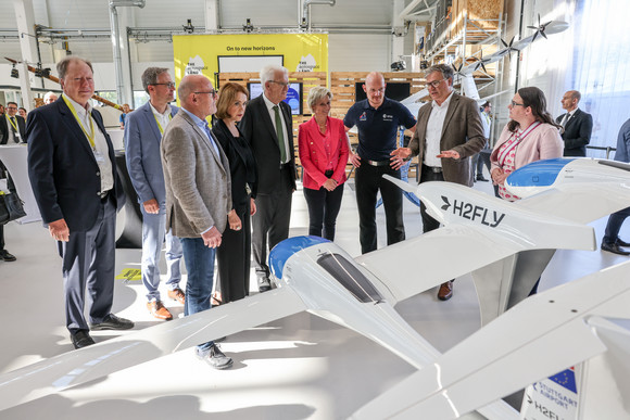 Innovationsoffensive Auftakt der Luft- und Raumfahrtstrategie des Landes Ministerpräsident Winfried Kretschmann und weitere Teilnehmende stehen bei einem Rundgang an einem Modell des Forschungs- und Versuchsflugzeugs HY4.