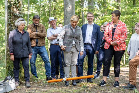 Beim ihrem Besuch der keltischen Viereckschanze Gerichtstetten bei Hardheim unterstützt Ministerin Razavi (Mitte) bei der Georadar-Messung