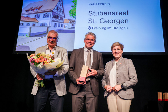 Denkmalpflege Verleihung Innovationspreis „Denkmal – Energie – Zukunft“ Ministerin Nicole Razavi MdL (rechts) überreicht den Innovationspreis für Stubenareal St. Georgen in Freiburg an Bürgermeister Stefan Breiter (Mitte) und Bruno Gramich, ehemaliger Leiter des Liegenschaftsamtes der Stadt Freiburg (rechts).
