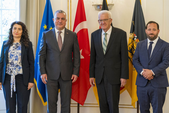 Antrittsbesuch Kretschmann empfängt türkischen Botschafter von links nach rechts: Generalkonsulin Makbule Koçak, Botschafter Ahmet Başar Şen, Ministerpräsident Winfried Kretschmann und Staatssekretär Florian Hassler stehen in der Villa Reitzenstein vor Fahnen.