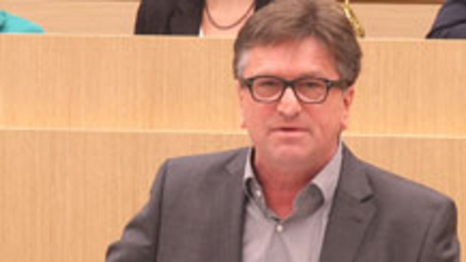 Manne Lucha, Minister für Soziales und Integration, steht im Landtag von Baden-Württemberg am Rednerpult.
