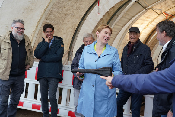 Staatssekretärin Andrea Lindlohr MdL mit dem Holzwerkzeug, das die frühkeltischen Erbauer der Grabkammer zurückgelassen haben