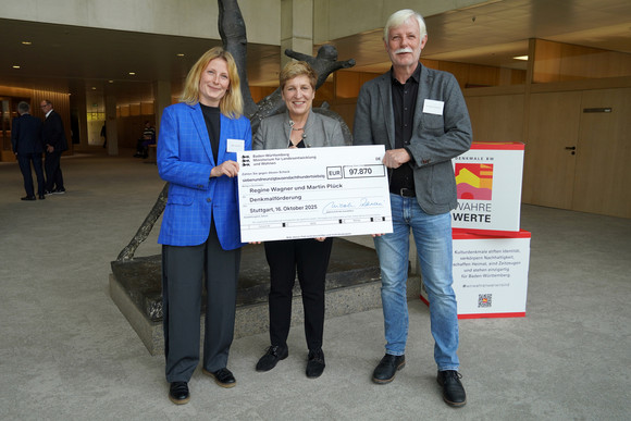 Denkmalpflege Zweite Tranche Denkmalförderung 2025: Symbolische Schecks v.l.: Architektin Alice Selbach, Ministerin Nicole Razavi MdL, Architekt Wolfgang Selbach